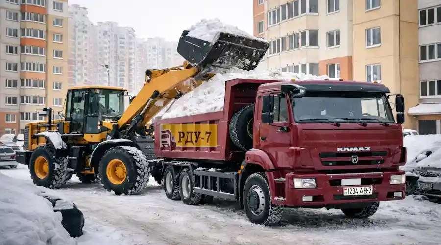 Вывоз и утилизация снега во дворе Минска - погрузчик грузит снег в самосвал КАМАЗ
